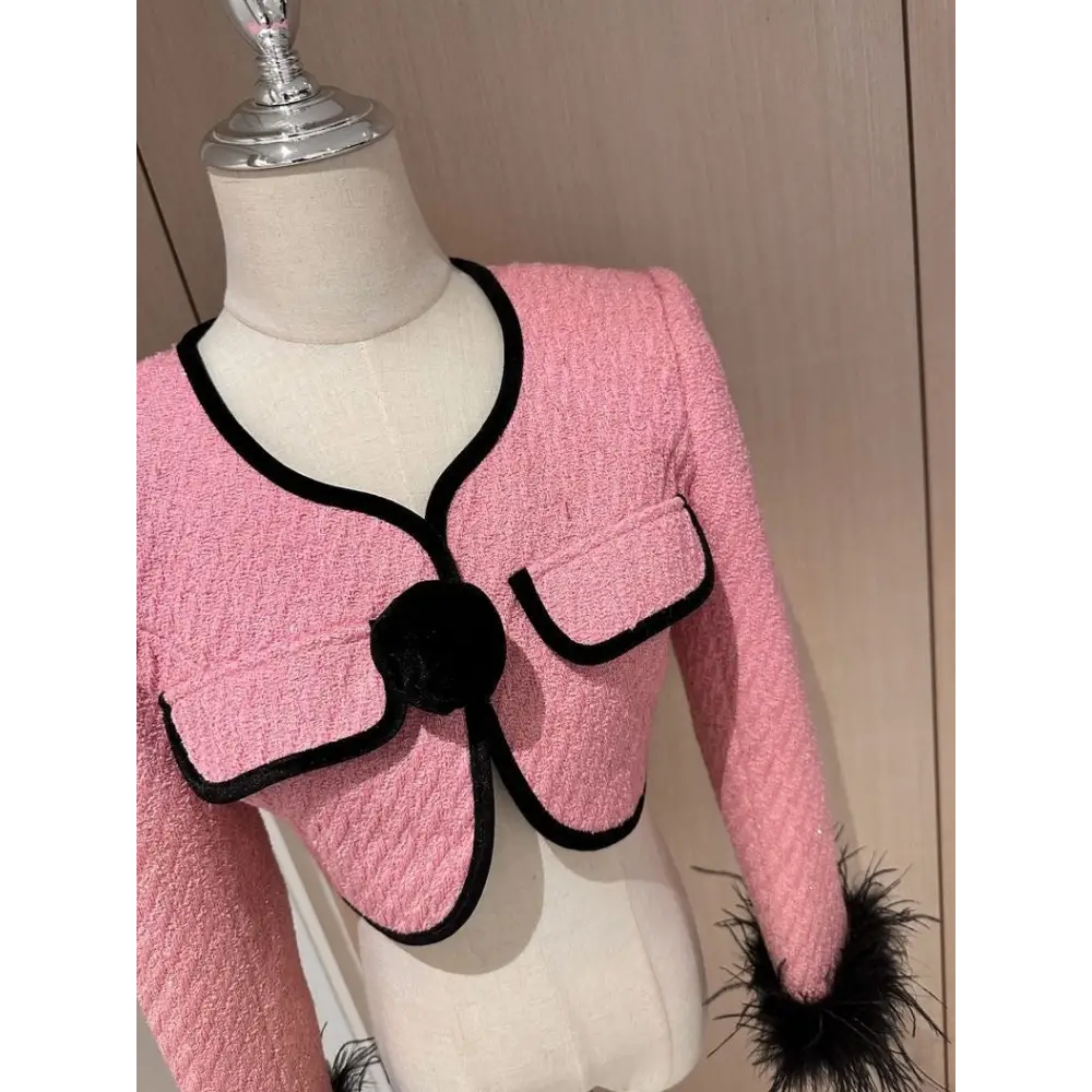 Pink tweed jacket with black trim.