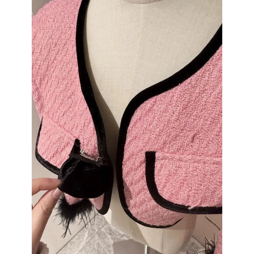 Pink tweed jacket with black trim.