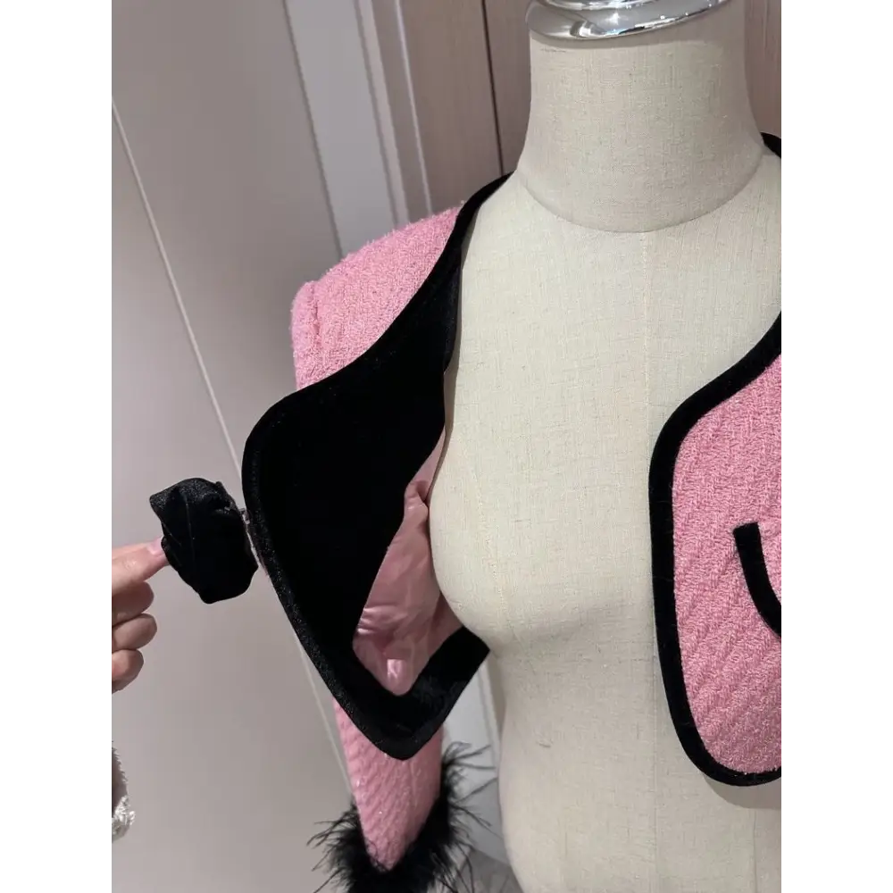 Pink tweed jacket with black trim.
