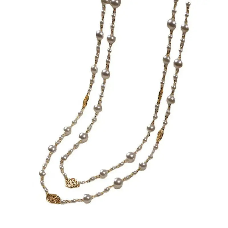 Long pearl necklace with gold accents.