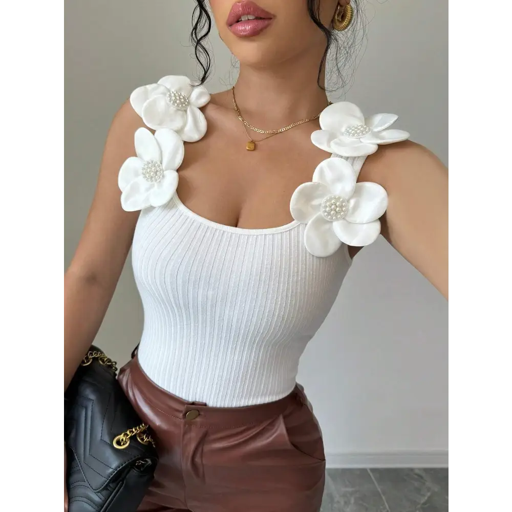 White ribbed tank top with floral shoulder embellishments.