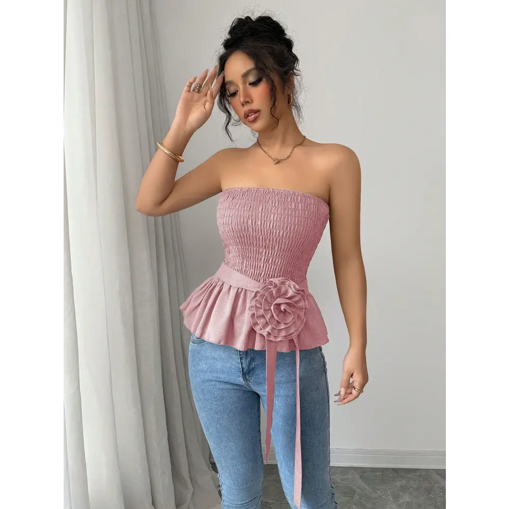 Woman wearing a pink strapless top and jeans.