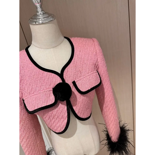 Pink tweed jacket with black trim.