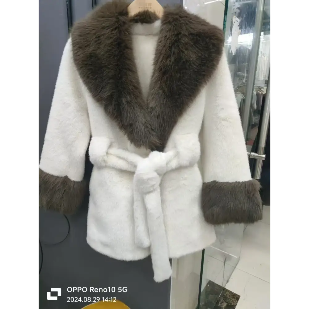 White faux fur coat with brown trim.