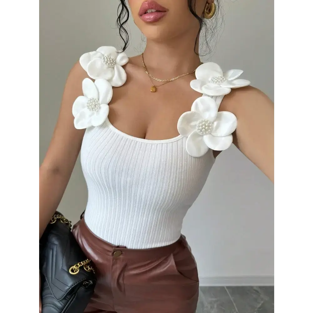 White ribbed tank top with floral shoulder embellishments.