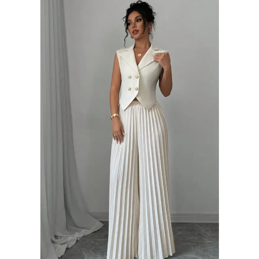 Woman in a white vest and pleated pants.