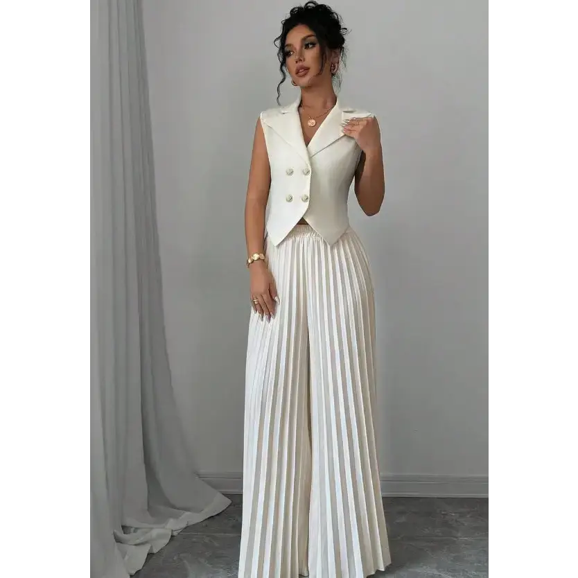Woman in a white vest and pleated pants.